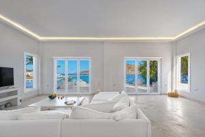 a white living room with white furniture and windows at Sunset Villa in Posidhonía