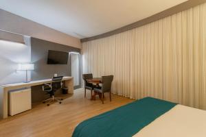 a hotel room with a bed and a desk with a computer at Suntory Hotel in Pará de Minas