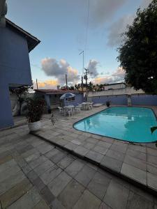 a small swimming pool on a patio with tables and chairs at Suítes Marrakesh in Porto De Galinhas