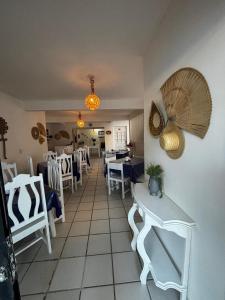a restaurant with white chairs and tables and a room with aoit at Suítes Marrakesh in Porto De Galinhas