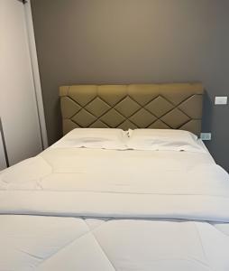 a bed with white sheets and a brown headboard at Hospedaria Santo Descanso (Edícula) in Uberlândia