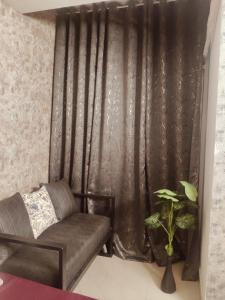 a living room with a couch and a curtain at StudeXO in Ghaziabad +1 photo