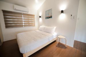 a bedroom with a bed with a window and a stool at Casita Benito Loft A in Sangley Point Naval Station