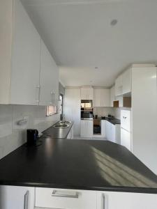 a kitchen with white cabinets and a black counter top at Villa Amari in Aliwal North