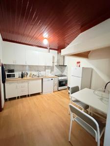 a kitchen with white cabinets and a table with chairs at Casa da Praça de Murça in Murça