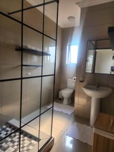 a bathroom with a glass shower stall and a toilet at The Pebbles-UA in Mahikeng