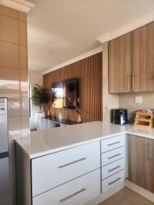 a kitchen with white counter tops and wooden cabinets at The Pebbles-UA in Mahikeng
