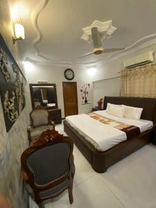 una camera da letto con un letto, una sedia e un orologio di Highland Lodge a Karachi