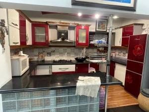 una cucina con mobili rossi e un piano di lavoro nero di Highland Lodge a Karachi