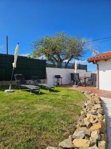 a backyard with chairs and an umbrella and a table at Casa de Aldea La Corexa in Bañugues