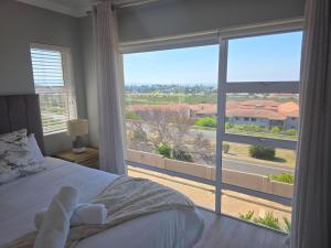 a bedroom with a bed and a large window at Heuwels Haven in Mossel Bay