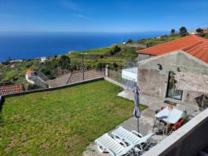 a patio with two lawn chairs and the ocean at Casa Rosinha, views & sunset in Calheta