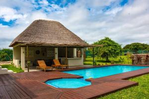 a house with a thatched roof and a swimming pool at Ka Nicita - Beach house with pool in Praia de Macaneta