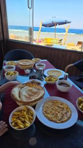a table with plates of food on a table with the beach at Ghazala hotel dahab in Dahab