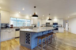 a large kitchen with a blue island with bar stools at 'Whispering Oaks Estate' w/ Pool & View in Murphys in Vallecito