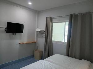 a bedroom with a bed and a tv and a window at Betong Chill House in Ban Hua Phrong