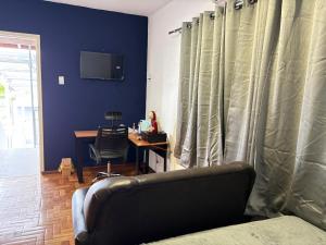 a living room with a couch and a desk and a television at Suite Privativa in Dom Pedrito