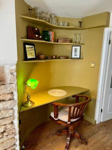 a desk in a room with a lamp and a chair at Matchbox Cottage in Frome