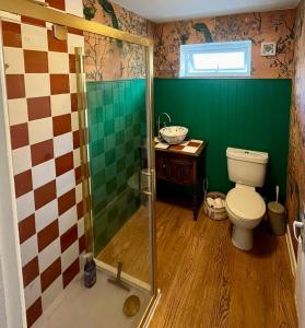 a bathroom with a toilet and a glass shower at Matchbox Cottage in Frome