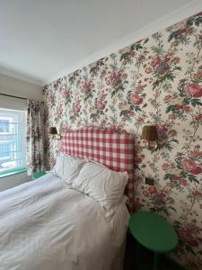 a bedroom with a bed with floral wallpaper at Matchbox Cottage in Frome