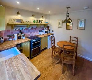 a kitchen with a wooden table and a table and chairs at Matchbox Cottage in Frome