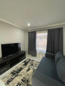 a living room with a couch and a flat screen tv at Villa Amari in Aliwal North