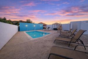 a patio with chairs and a swimming pool at sunset at HOTEL LARIMAR - Valle de Guadalupe in Dinuva