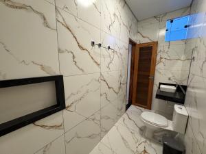 a bathroom with a toilet and a marble wall at Pousada Serena - Alter do Chão in Santarém +23 photos