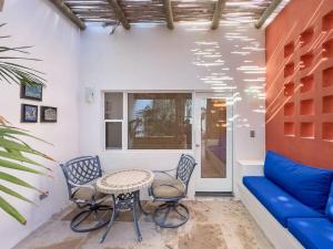 a patio with a table and chairs and a blue couch at Casa Ruma Beachfront Art House in Bahía Kino
