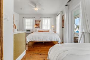 a white bedroom with two beds and a ceiling fan at NIGHTCAP @ Speakeasy Inn Key West! in Key West