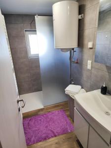 a bathroom with a purple rug next to a sink at DAI Apartment in Maribor +18 photos