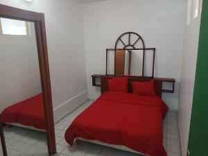 a bedroom with a red bed and a mirror at Haut de Villa Manguier in Petit-Bourg