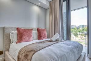 a bedroom with a large bed with pink pillows at Caica Executives at Ellipse 4108 in Midrand +17 photos