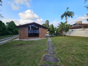 a house with a stone path in front of a yard at Casa Enorme em condominio, 4 suites, piscina com cascata, cozinha gourmet com churrasueira e fundo com pier no rio para práticas aquaticas in Bertioga