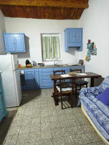 a kitchen with blue cabinets and a table and a refrigerator at Sa Domitta di Suiles in Olbia