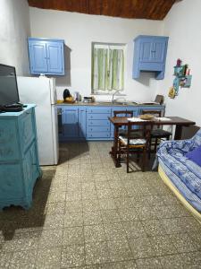a kitchen with blue cabinets and a table and a refrigerator at Sa Domitta di Suiles in Olbia