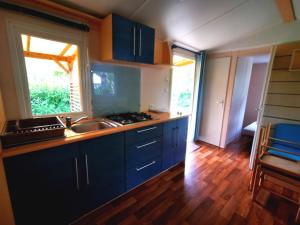 a kitchen with blue cabinets and a sink at Camping le Terriol - Onlycamp in Cajarc