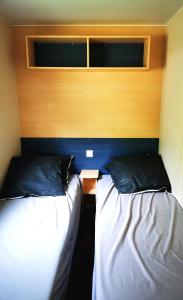 two beds in a bedroom with a headboard and a table at Camping le Terriol - Onlycamp in Cajarc +26 photos