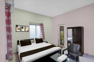 a hotel room with a bed and a table and a chair at Hotel O Candel Light Inn in Bhubaneshwar +22 photos