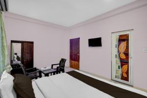 a bedroom with a bed and a table and a window at Hotel O Candel Light Inn in Bhubaneshwar