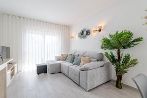 a living room with a couch and a palm tree at Sunset Terrace House by Destiny Houses in Esmoriz