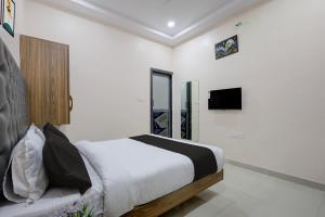 a bedroom with a bed and a tv on the wall at Super HOTEL O MATRI CROWN in Raipur +27 photos
