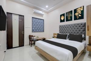 a bedroom with a large bed and a table at Super HOTEL O MATRI CROWN in Raipur
