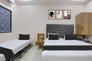 two beds in a room with white walls at Super HOTEL O MATRI CROWN in Raipur