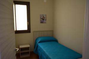 a small bedroom with a blue bed and a window at La casa di Bice alloggio 1 in Cassibile
