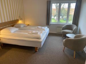 a bedroom with two beds and a chair and a window at Hotel Villum in Sandvig