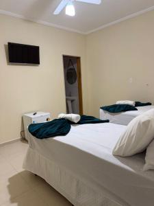 two beds in a room with a tv on the wall at Hotel e Pousada Santa Helena in Potim