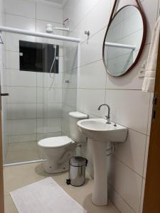 a bathroom with a toilet and a sink and a mirror at Hotel e Pousada Santa Helena in Potim