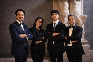 a group of four people in suits standing in front of a statue at Dimore Sangiuliano in Catania