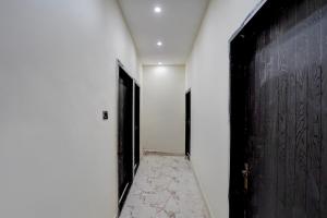 a hallway with a black door and a tile floor at Hotel O J K Galaxy Hotel in Juhi Bari